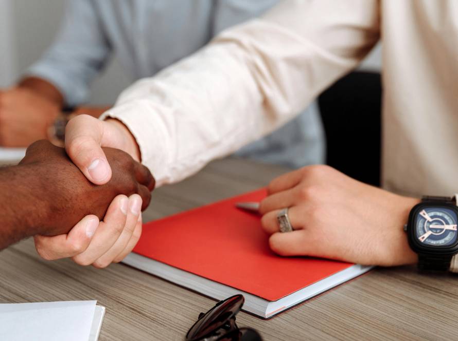 Two people shaking hands over documents