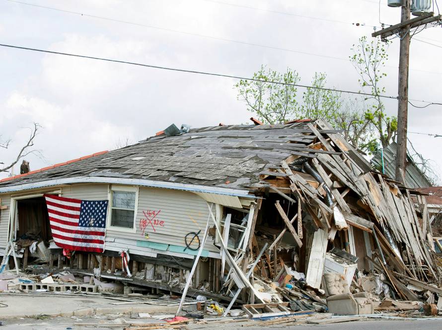 Storm-damaged house with American flag