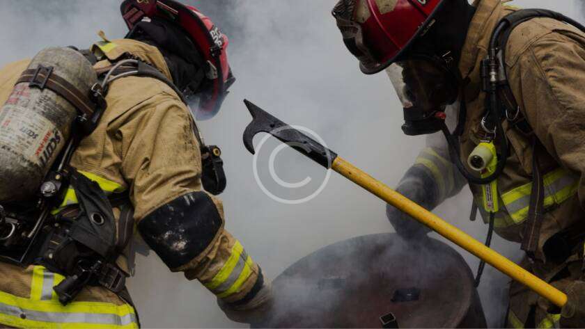 Two firefighters using pike pole amid smoke