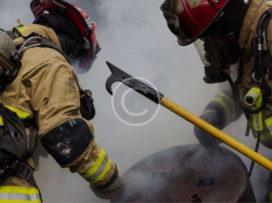 Two firefighters using pike pole amid smoke